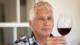 An older man holds and looks through a glass of red wine.
Ridofranz/iStock via Getty Images Plus