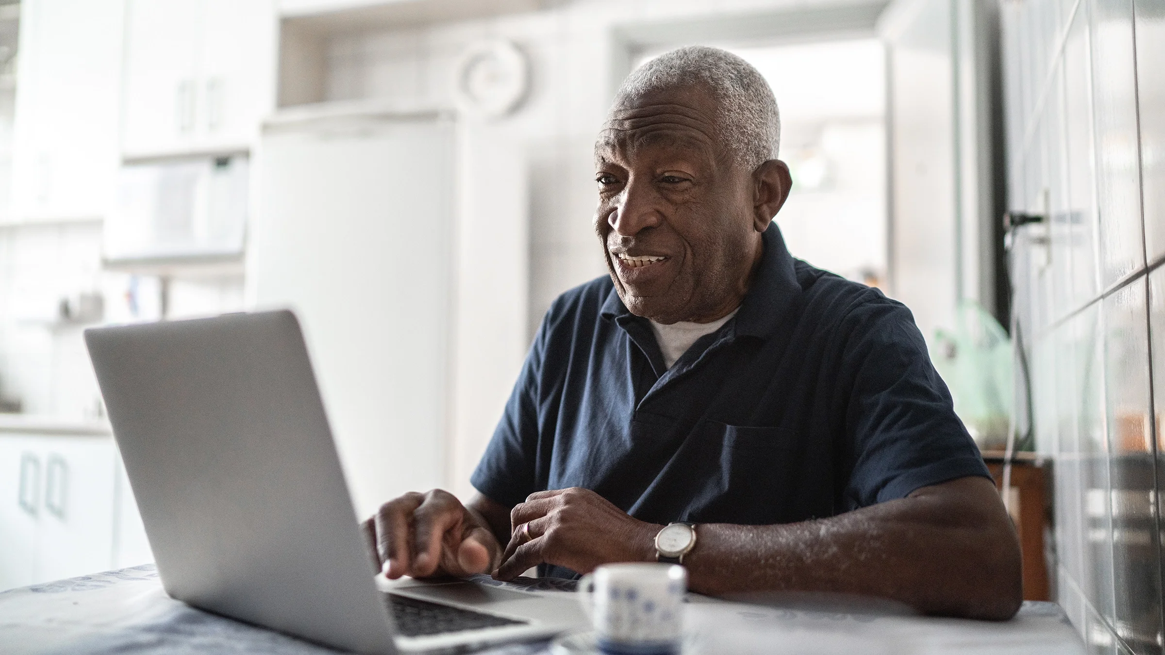 An older man is using his laptop at home.