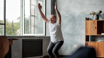 Movement exercise: senior man doing yoga chair pose 1177407582