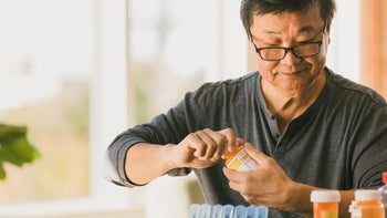 Health: Medication education: senior man opening prescription bottle 1295099861