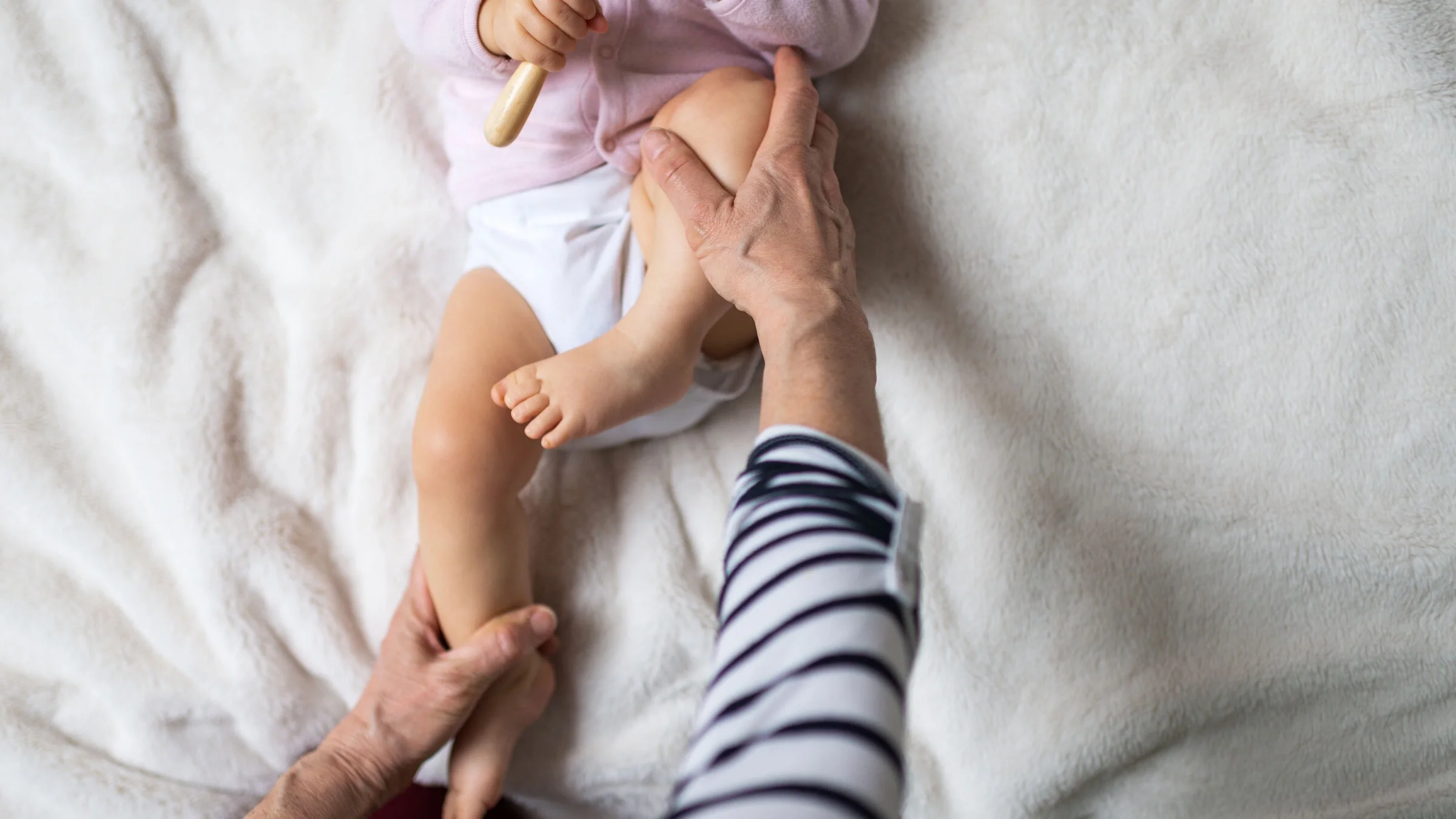 A person holds a baby’s leg and stretches it. Children with hip dysplasia who get treatment earlier have better outcomes. 