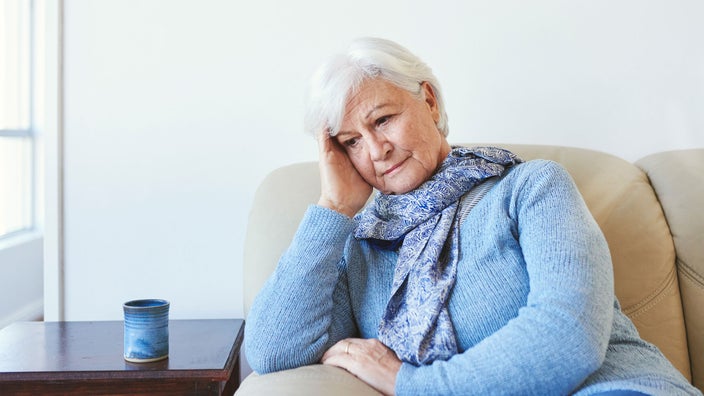 A senior woman looks unhappy at home.