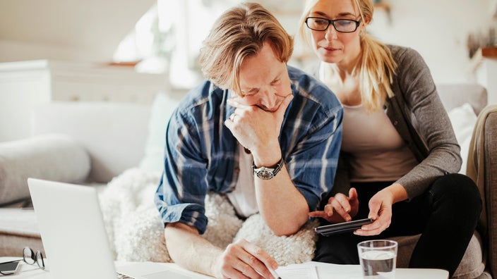 A couple calculates finances at home.