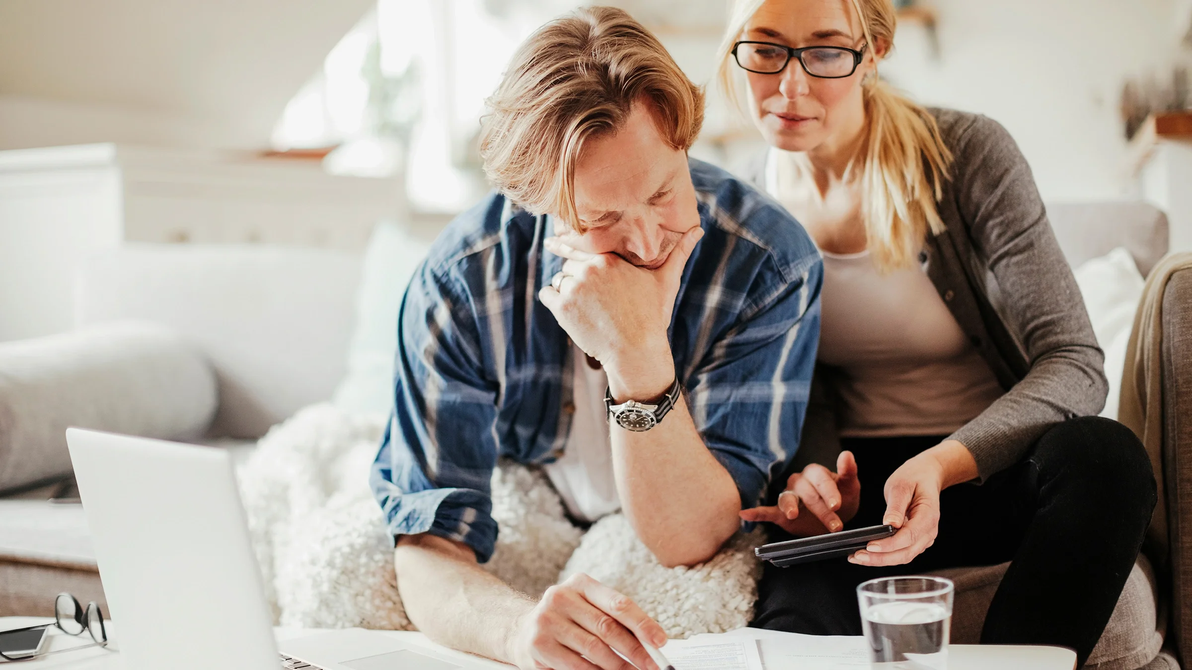 A couple calculates finances at home.