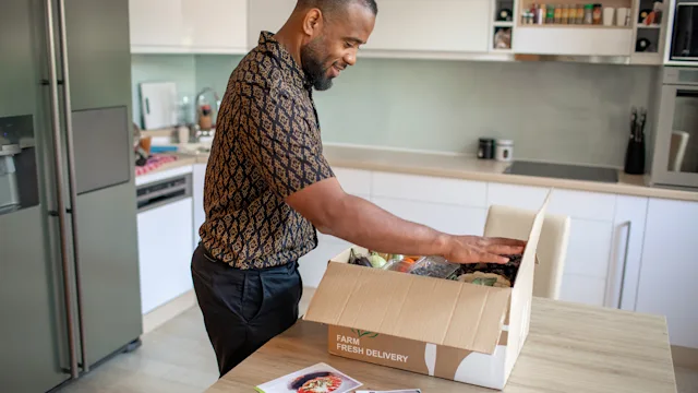 Diet and nutrition: man opening meal kit 1170736700