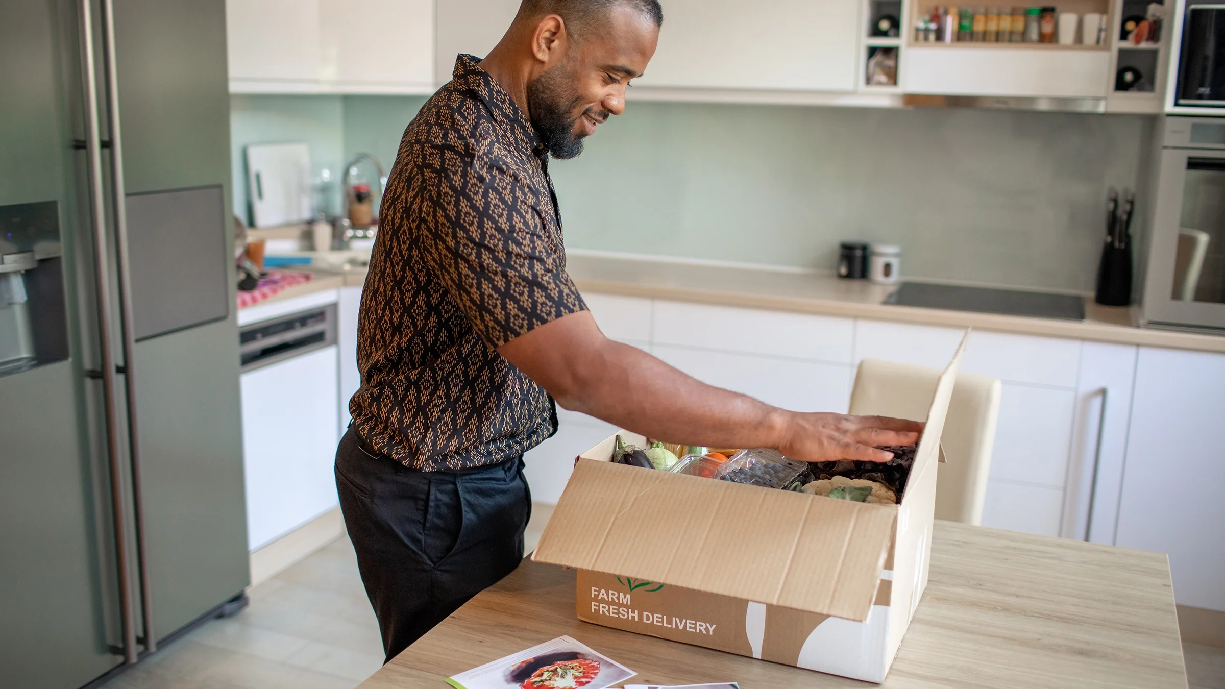 Man opening box with a meal delivery kit.