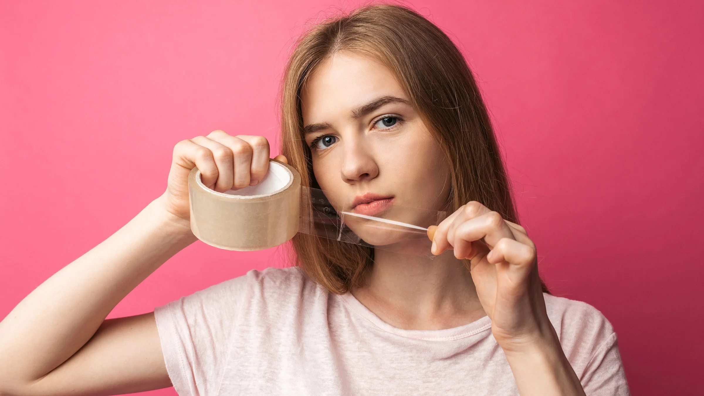 A teenager holding tape near their mouth.