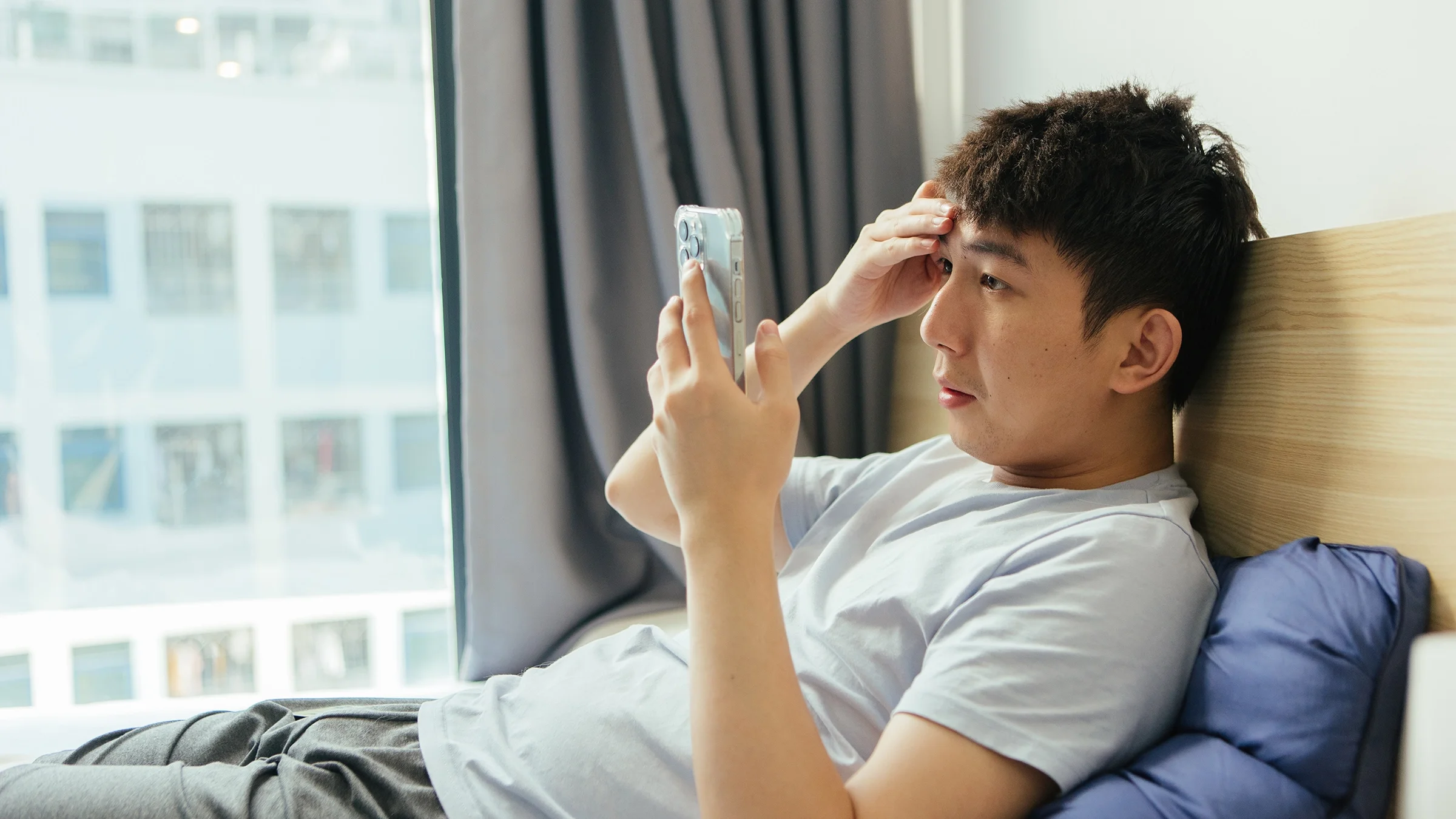 A man reads on his mobile phone in bed.