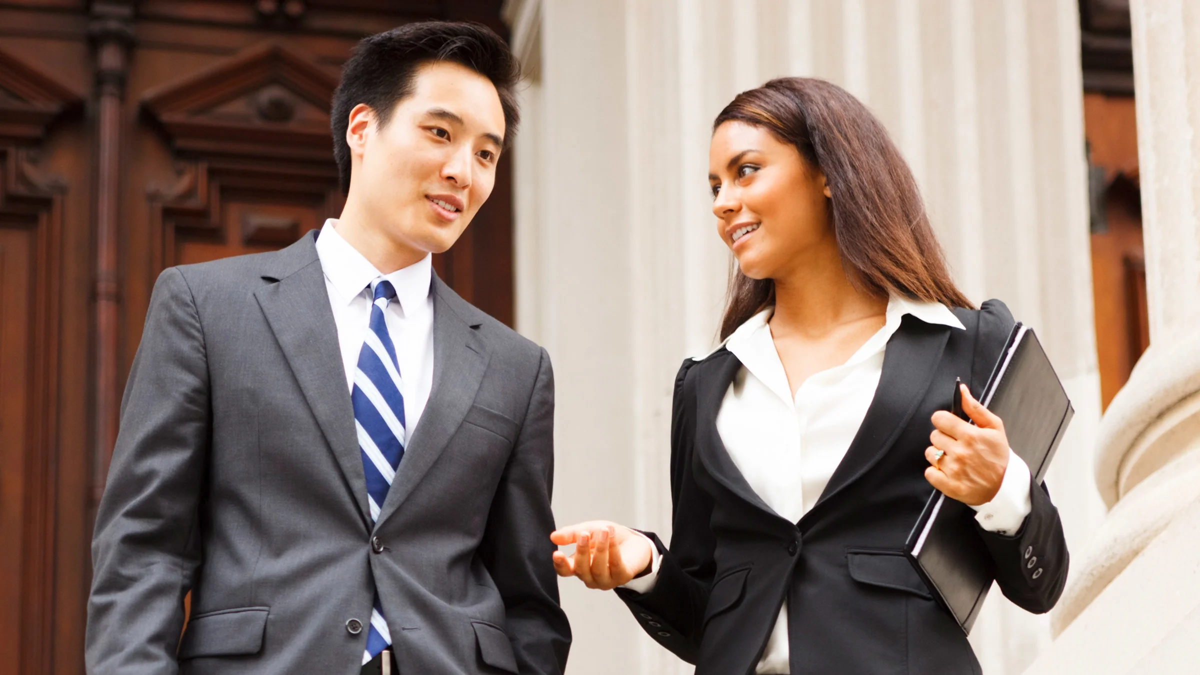 A lawyer and their client talking outside of a courthouse.