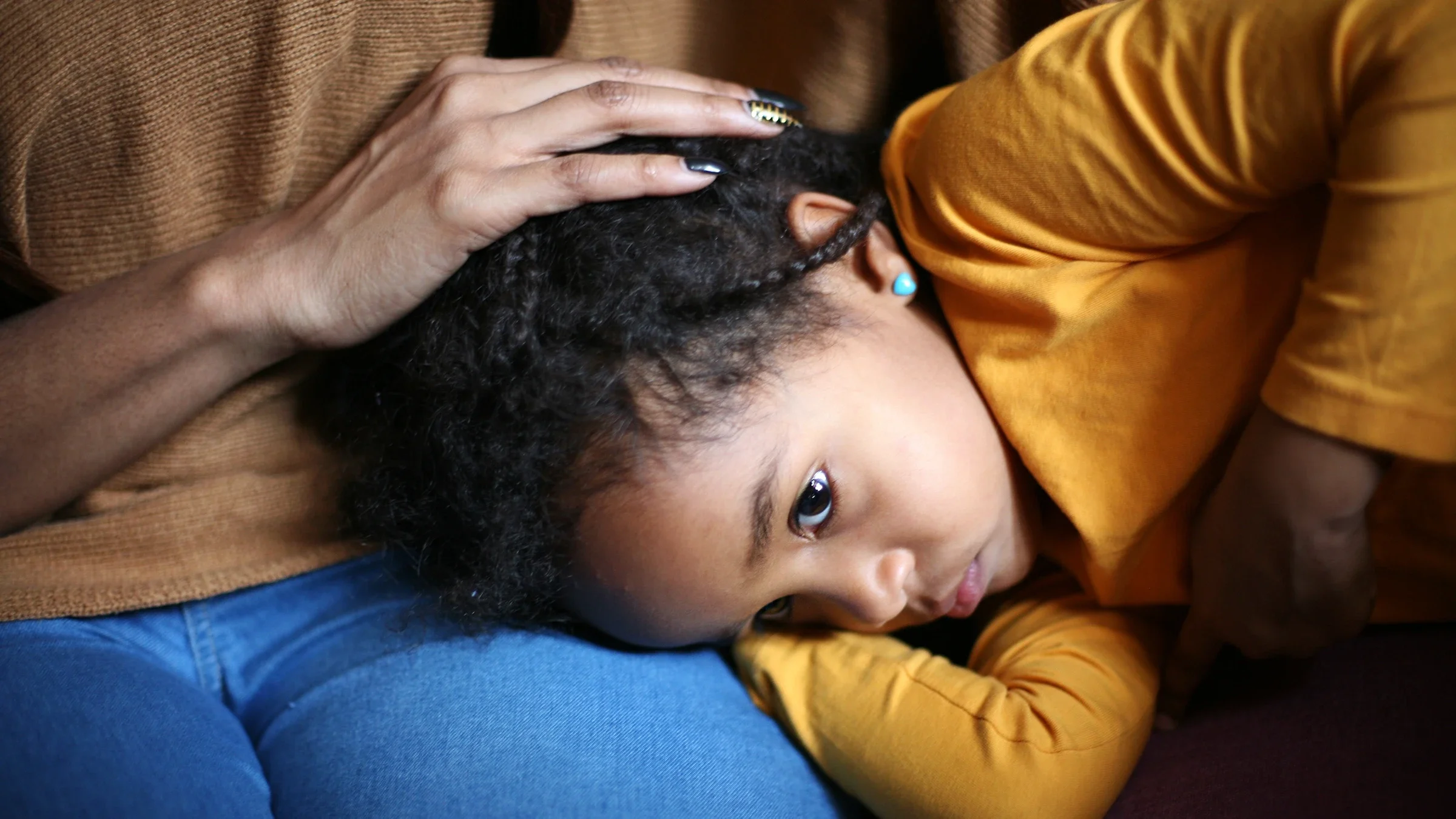 Child feeling ill and laying in mother's lap.