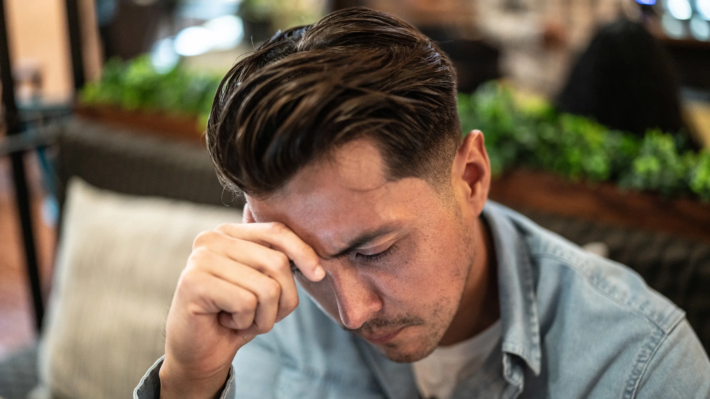 A person with a headache in a coffeeshop.