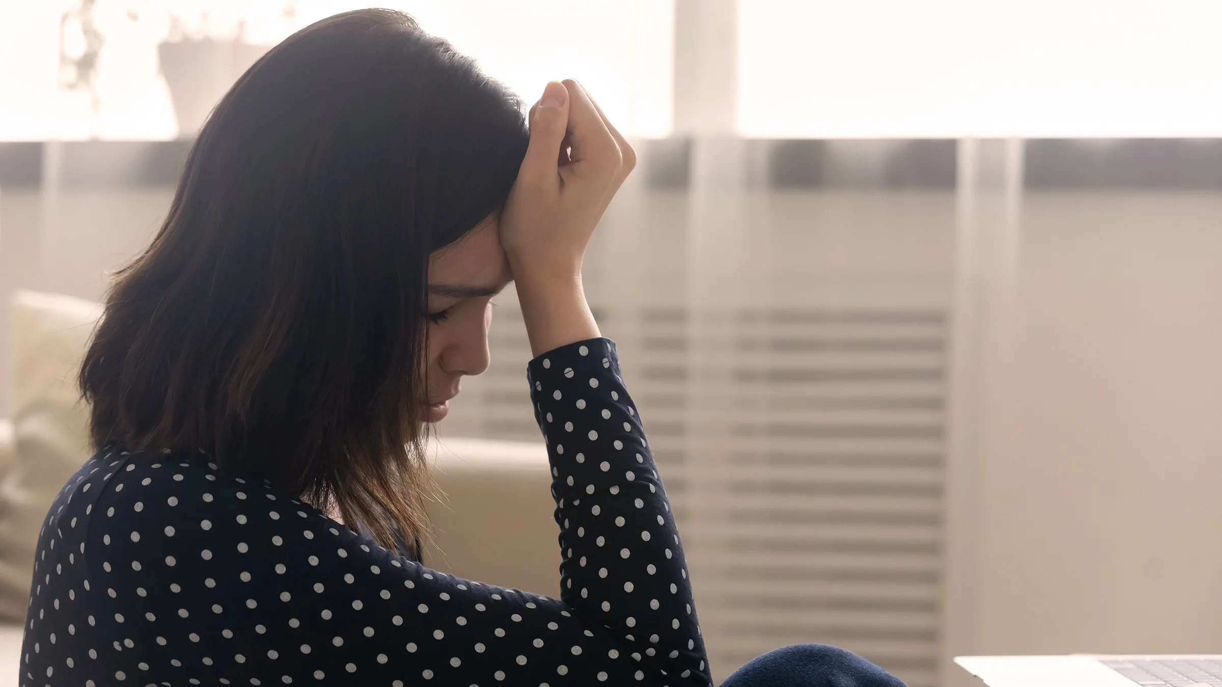 Woman reviewing health insurance documents with her hand on her forehead in frustration.