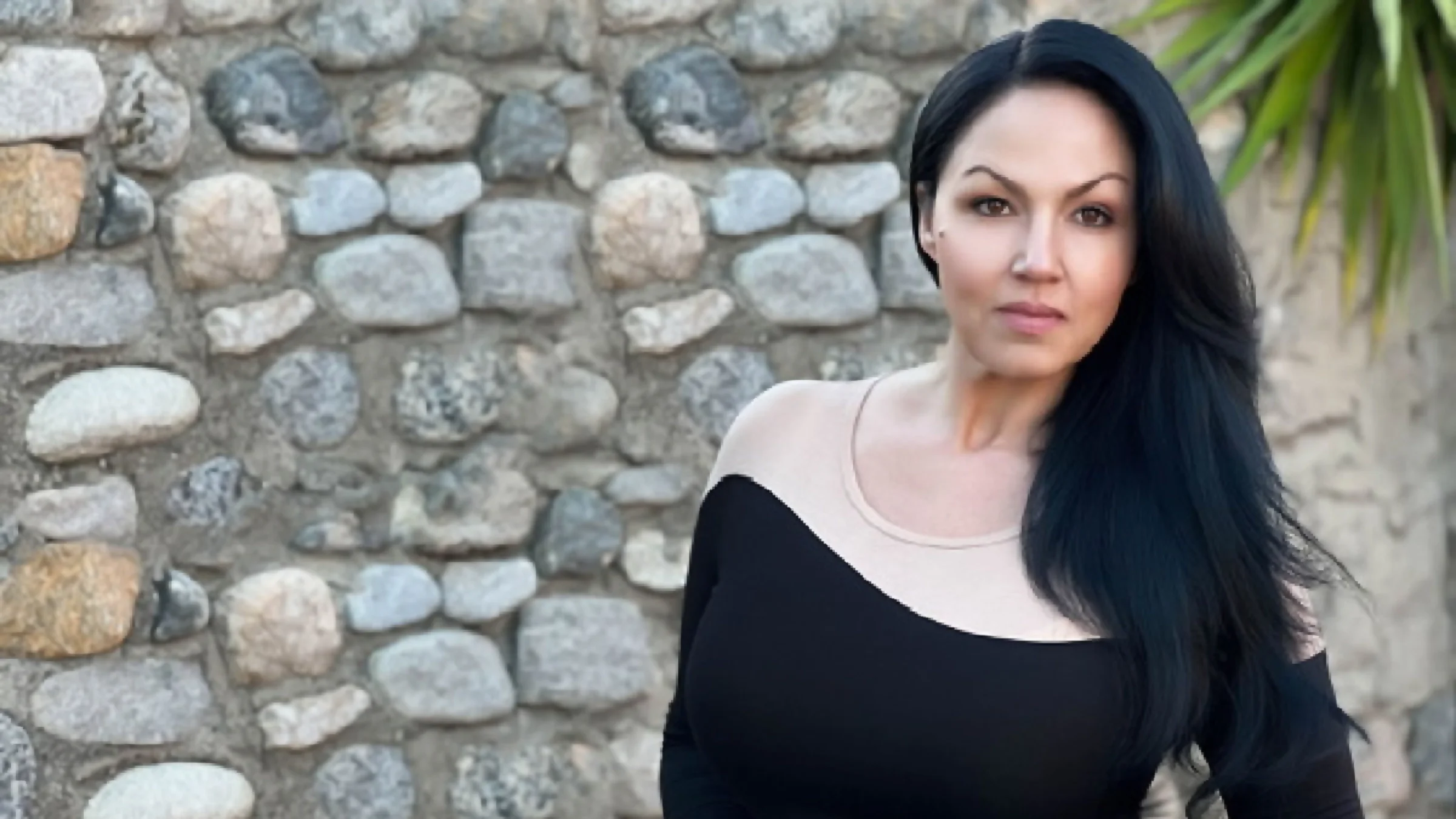 Shannon Lee is pictured in an environmental portrait, standing outside in front of a rock wall.