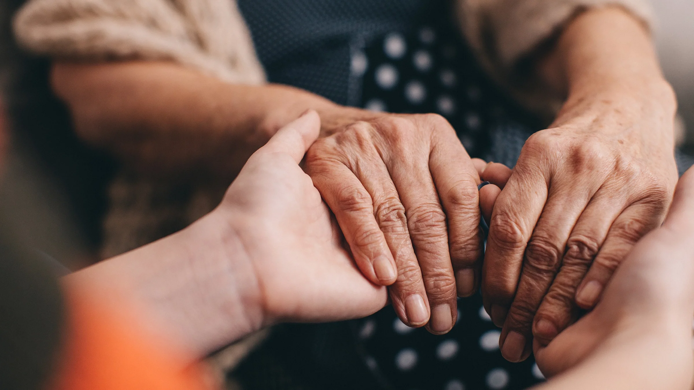 Close-up photo of hand holding in support. The focus is soft with a shallow depth of field.