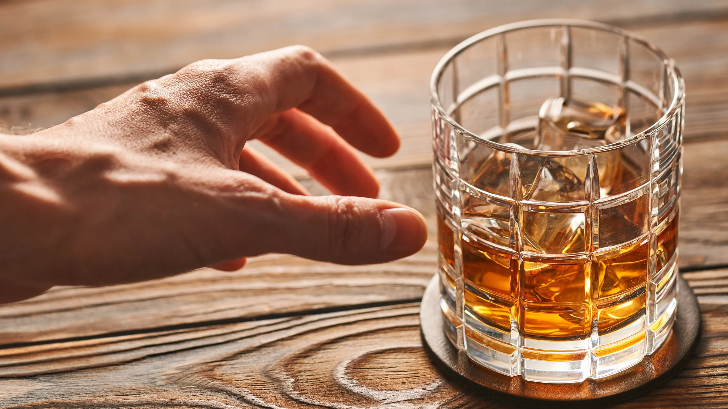 Hand reaching for whiskey glass.