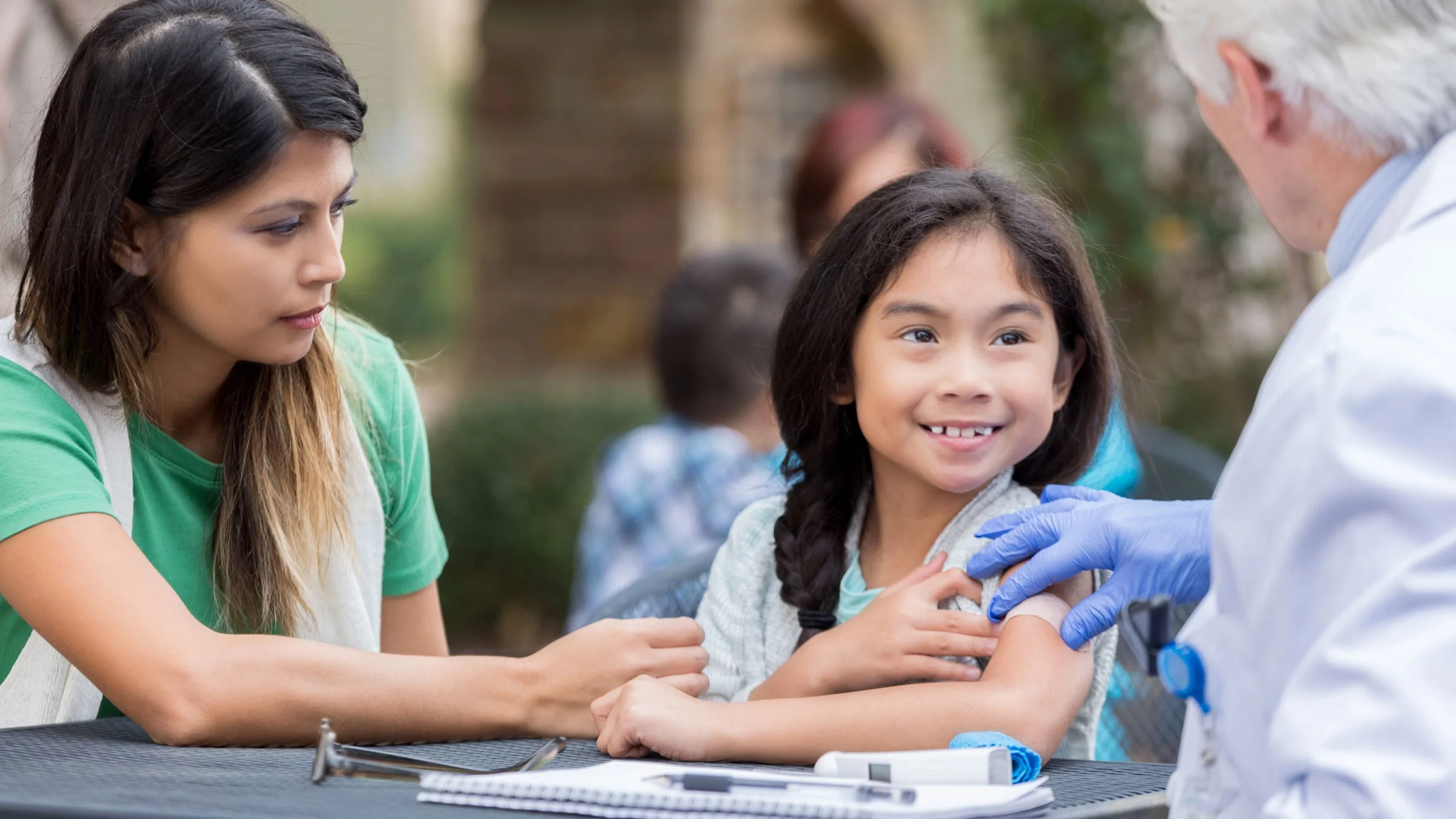 Girl receiving shot at free outdoor clinic.