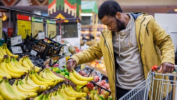 diet-nutrition: man choosing bananas in grocery store 1965121925