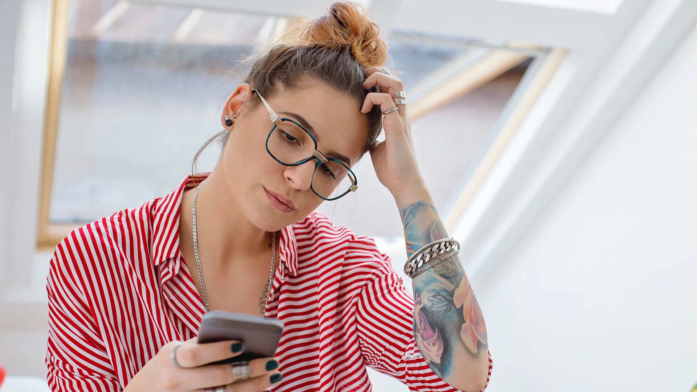 A person looking at their phone and scratching their head thinking.