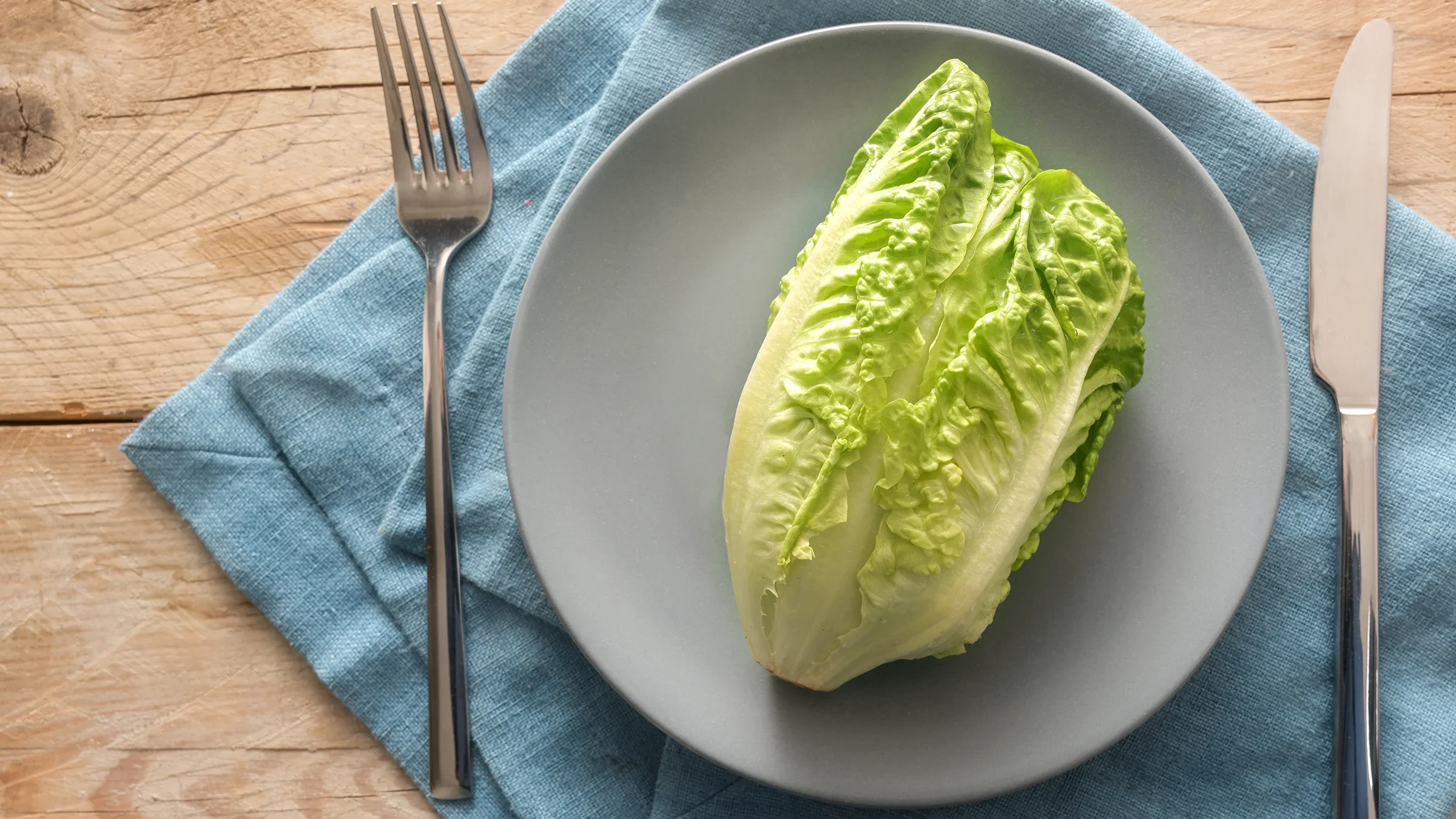 A head of romaine lettuce lies on a plate.
fermate/iStock via Getty Images Plus