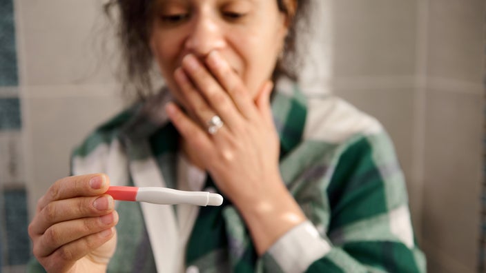 A woman looks at an at-home pregnancy test. 