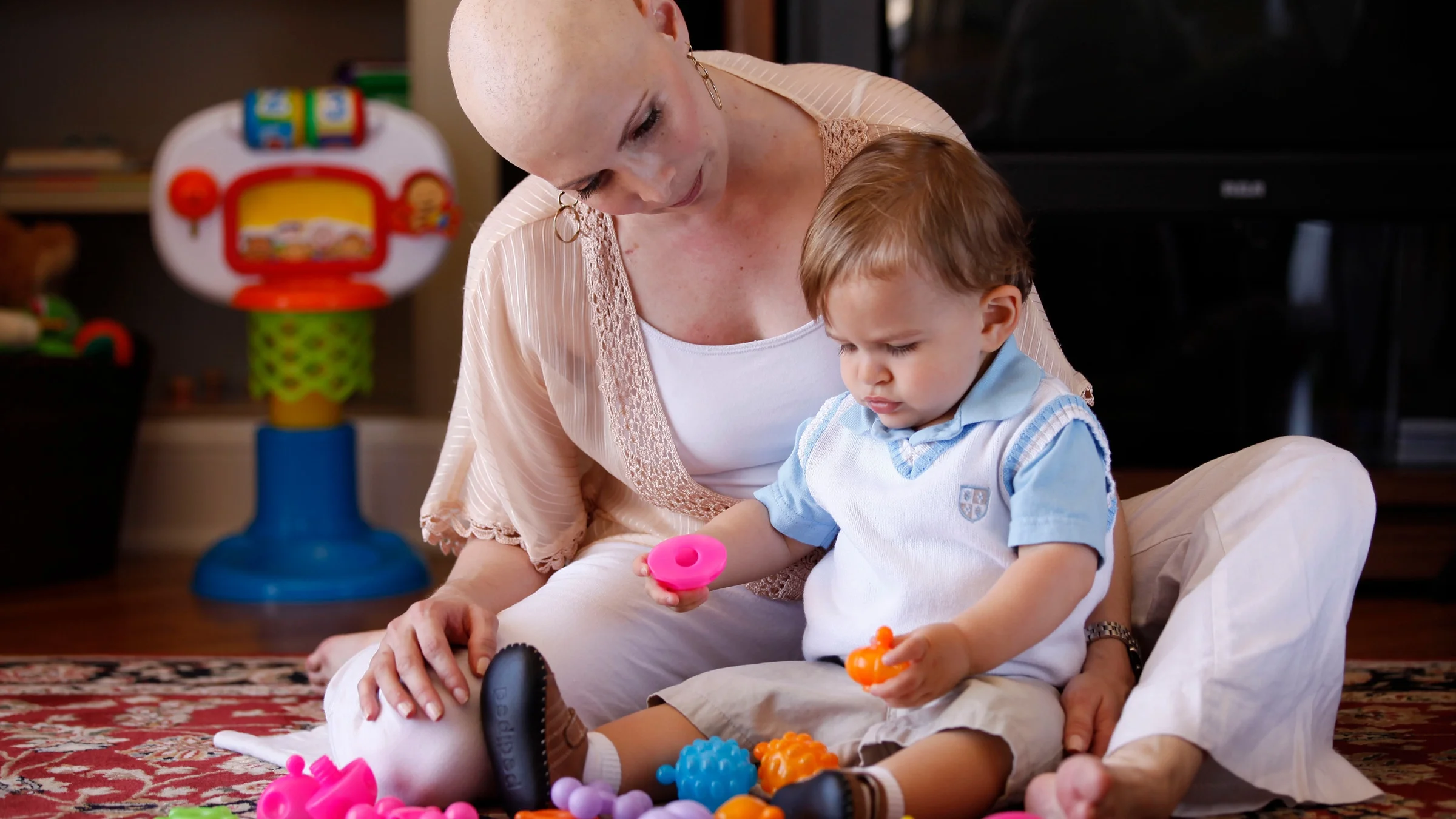 Seven-time Olympic medalist Shannon Miller is pictured playing with her toddler son after her ovarian cancer diagnosis. Shannon lost her hair during treatment.