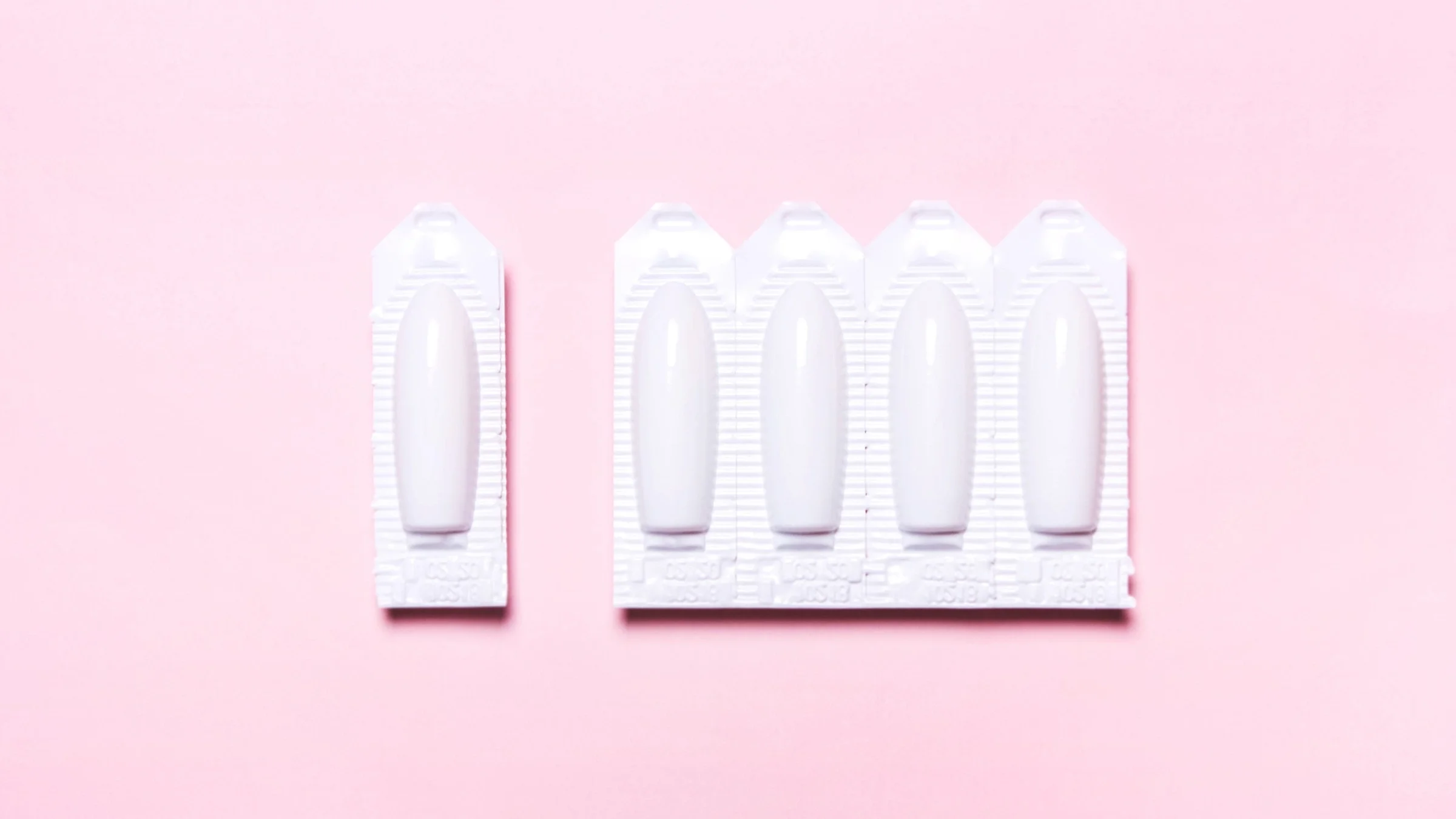 Package of yeast infection suppositories on a light pink background.