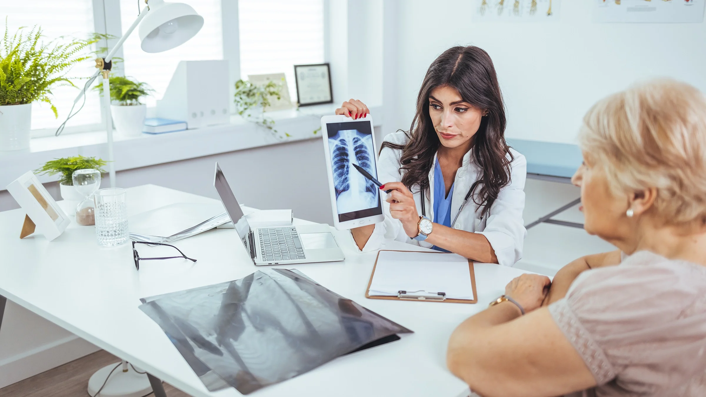 A doctor shows a chest X-ray to an older adult.