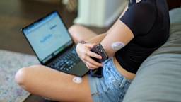 A person checks their continuous glucose monitor with a smartphone and a laptop.
FatCamera/E+ via Getty Images