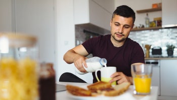 Diet and nutrition: man pours creamer into coffee mug 981879286