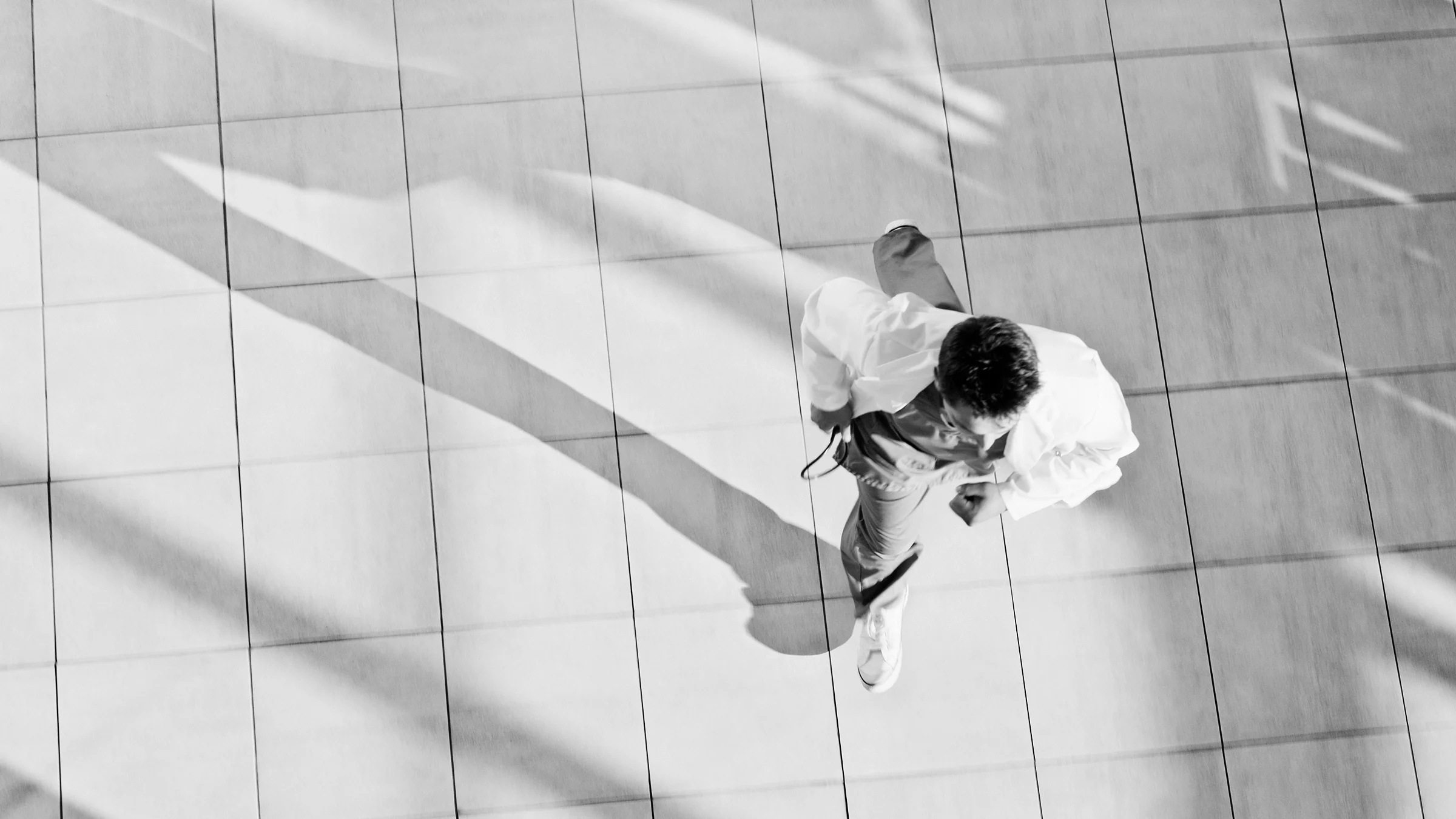 Black and white overhead shot of a doctor running in the hospital hallway.