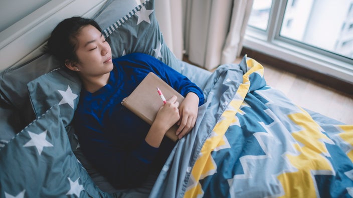 A person napping while hugging their journal.
