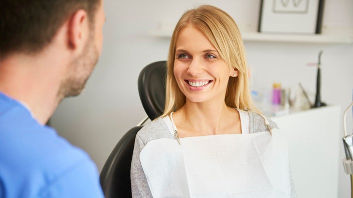 Portrait of a woman smiling at her dentist while she is in the exam chair.