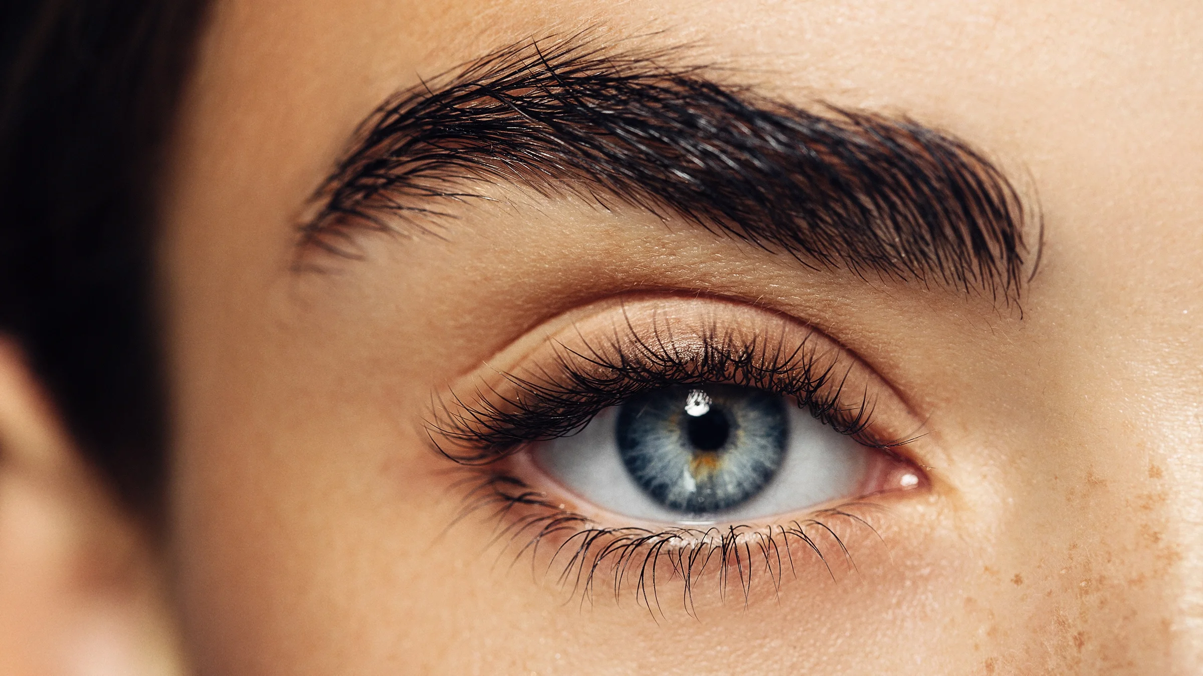 An eye with long, thick eyelashes is shown in a close-up.