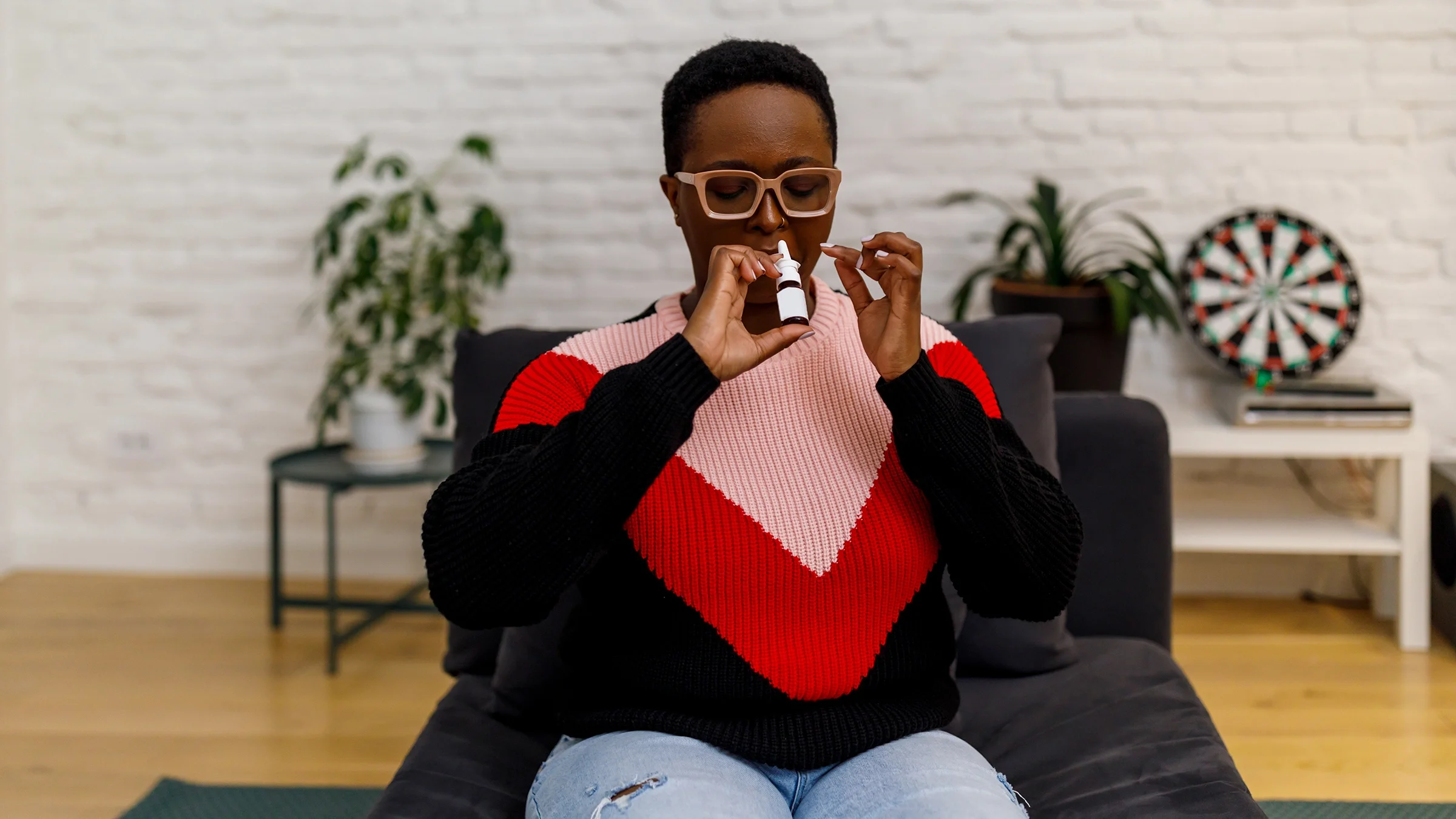 A woman uses a nasal spray at home.