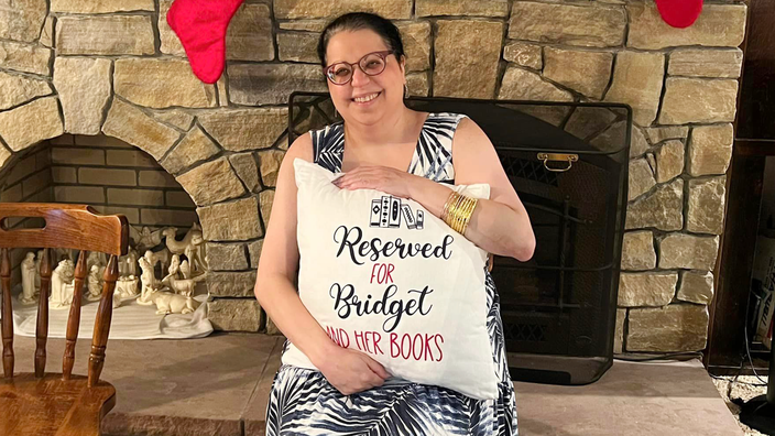 Bridget Noujaim is pictured holding a pillow she got as a Christmas gift that says: “Reserved for Bridget and her books.”