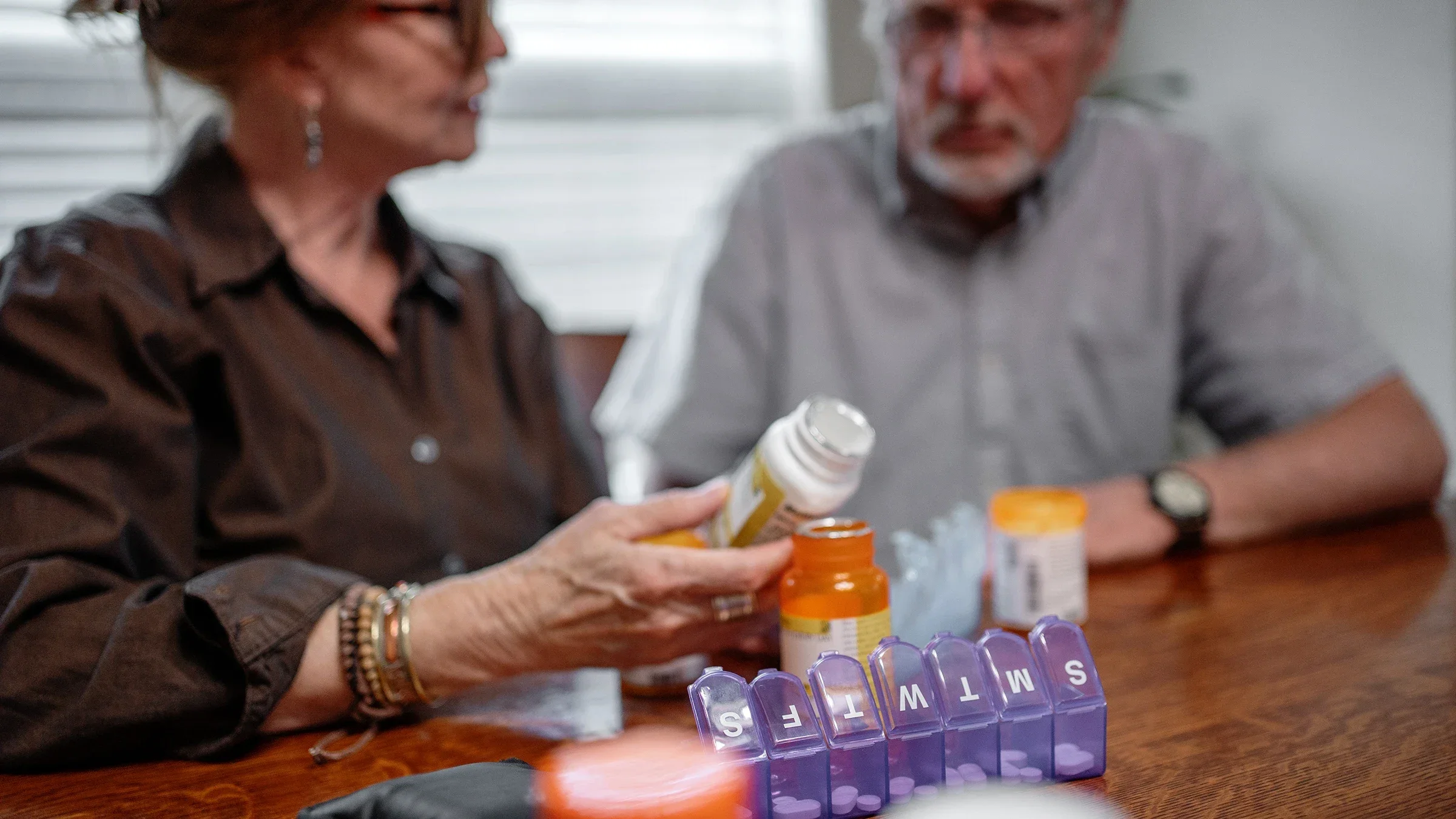 A couple places medication into a weekly pill organizer.
grandriver/E+ via Getty Images 