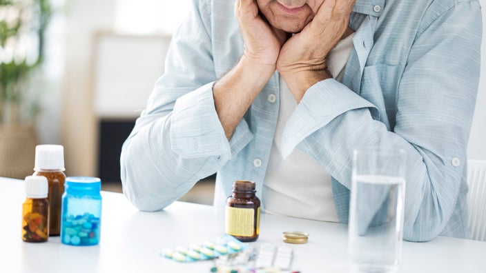 Một người đàn ông cao cấp nhìn xuống những viên thuốc và suy nghĩ.