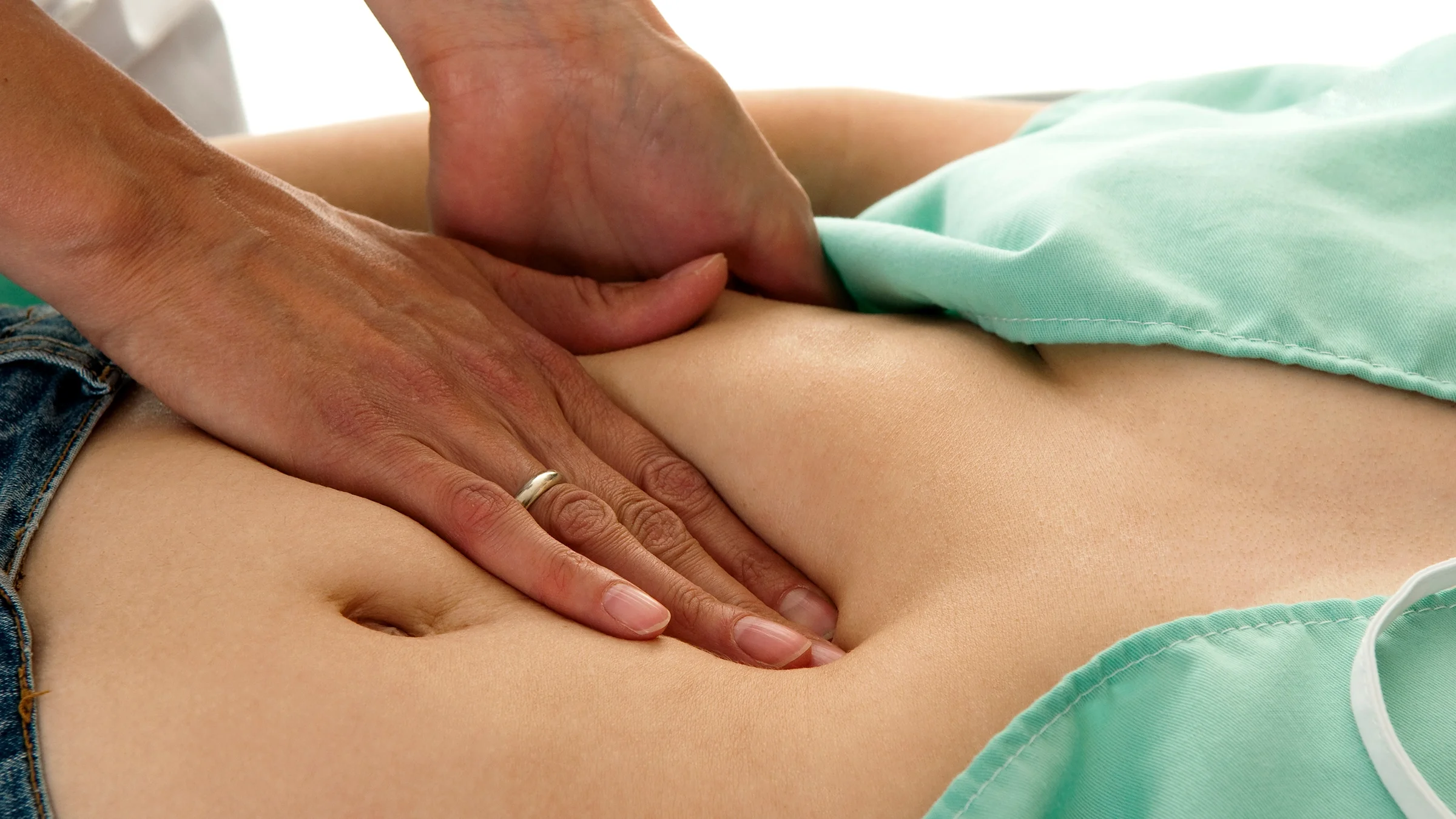 Close-up on an abdominal exam. The provider is pressing into a stomach and checking for resistance.