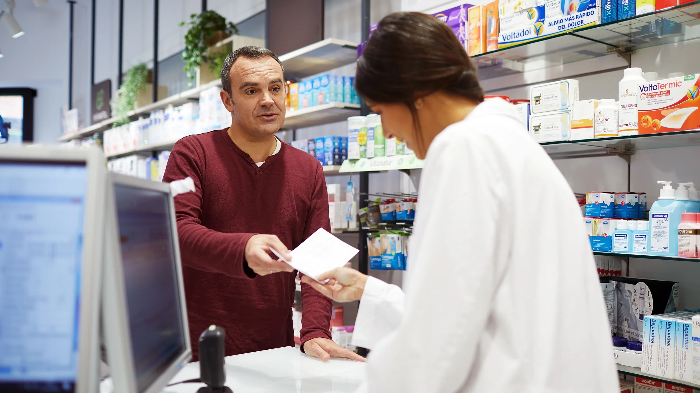 A customer hands a prescription to a pharmacist.