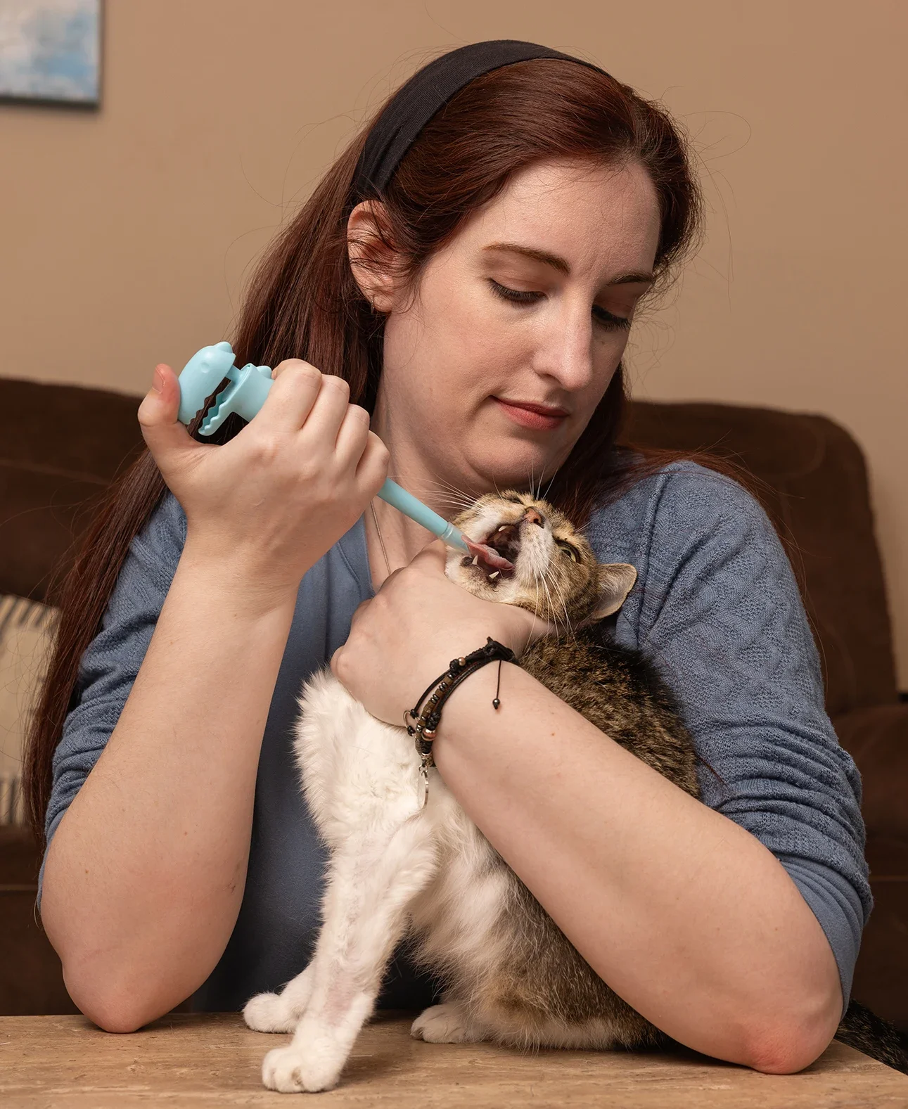 Kayla Delcoure is pictured giving her cat medication with a pill-popper device.