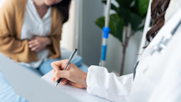 Doctor taking notes of patient with stomach pain.
Kiwis/iStock via Getty Images Plus

