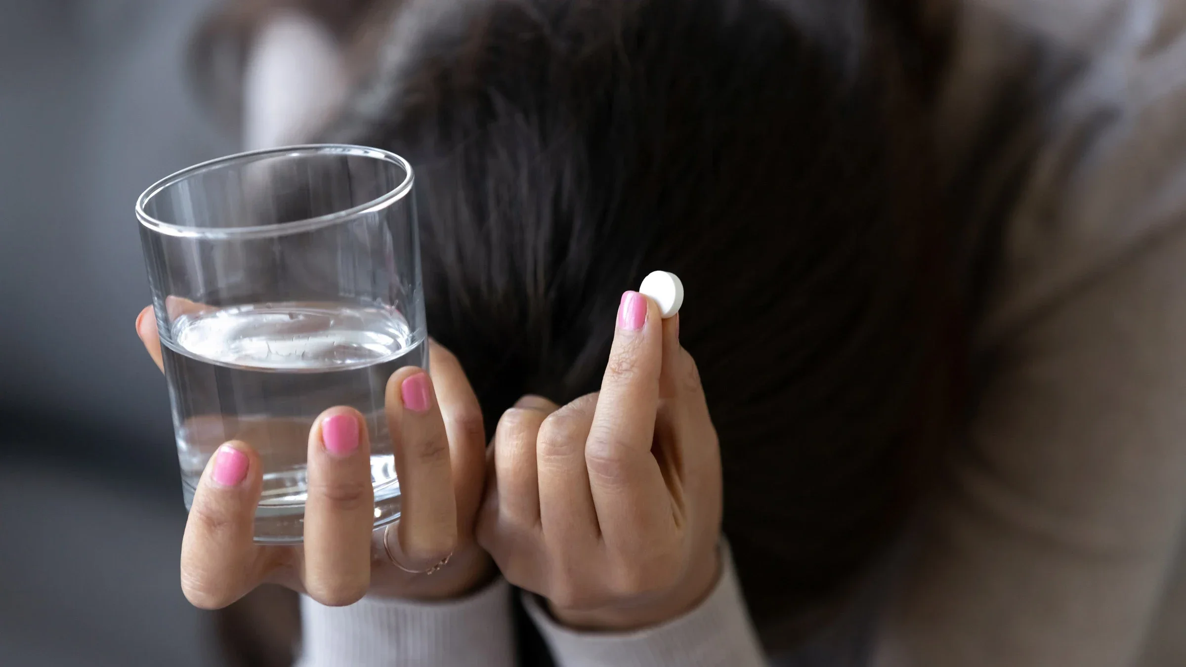 A depressed person holding a pill and glass of water.
fizkes/iStock via Getty Images Plus 