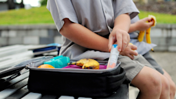 Cropped shot of a little boy eating lunch on the playground. He is reaching into his lunch box to grab his epipen.
CarrieCaptured/iStock via Getty Images