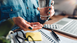 Close-up woman taking daily medication sitting at desk.
Kerkez/iStock via Getty Images Plus