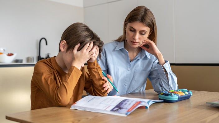 A student looking stressed out while doing homework with a tutor.