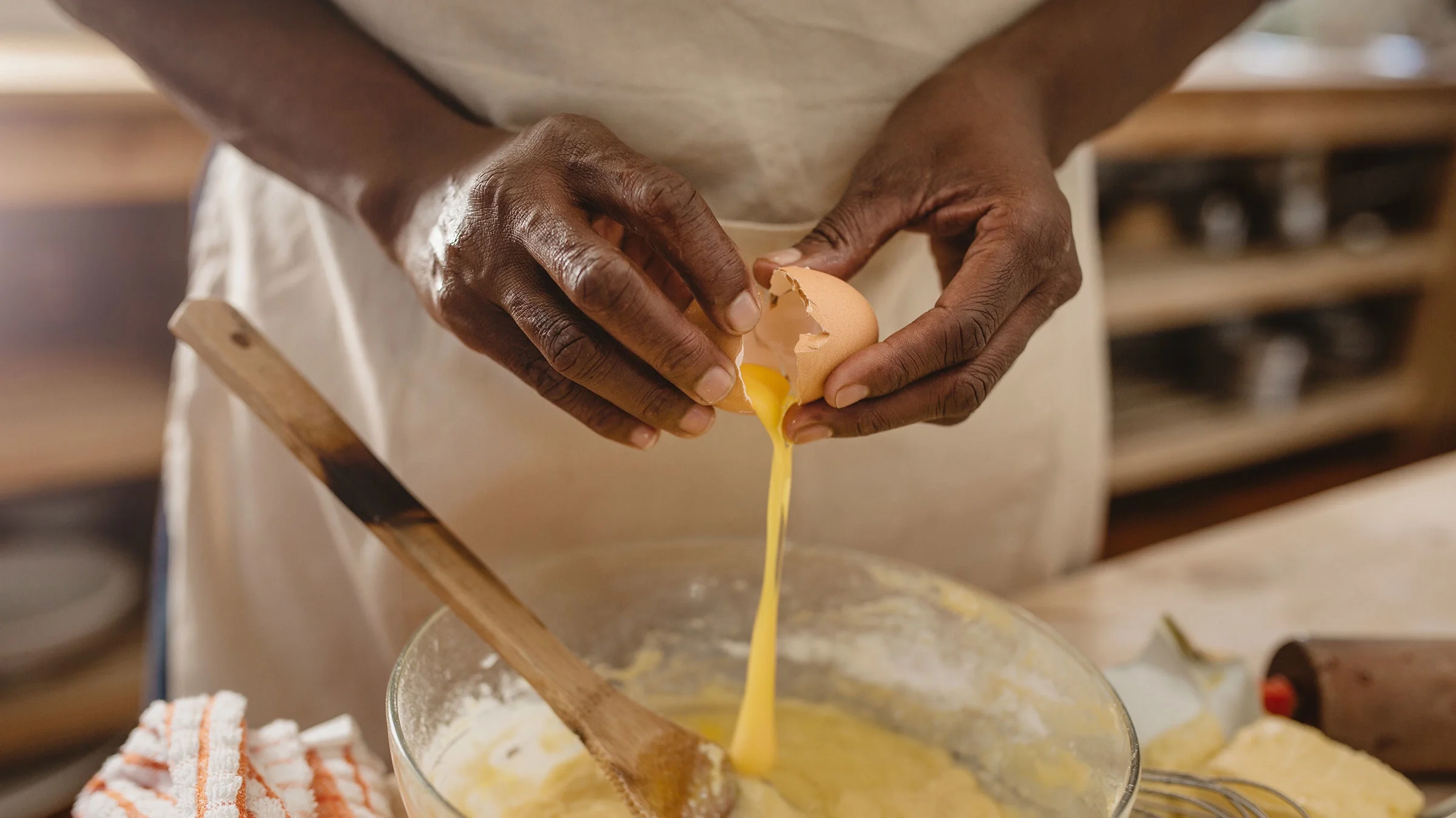 A woman cracks an egg into a bowl.