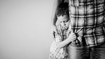 Health: SSKI: black and white little boy hugging dads leg-871113214