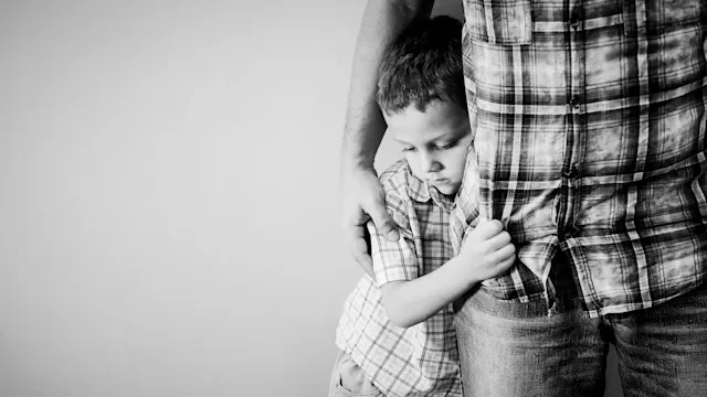 Health: SSKI: black and white little boy hugging dads leg-871113214