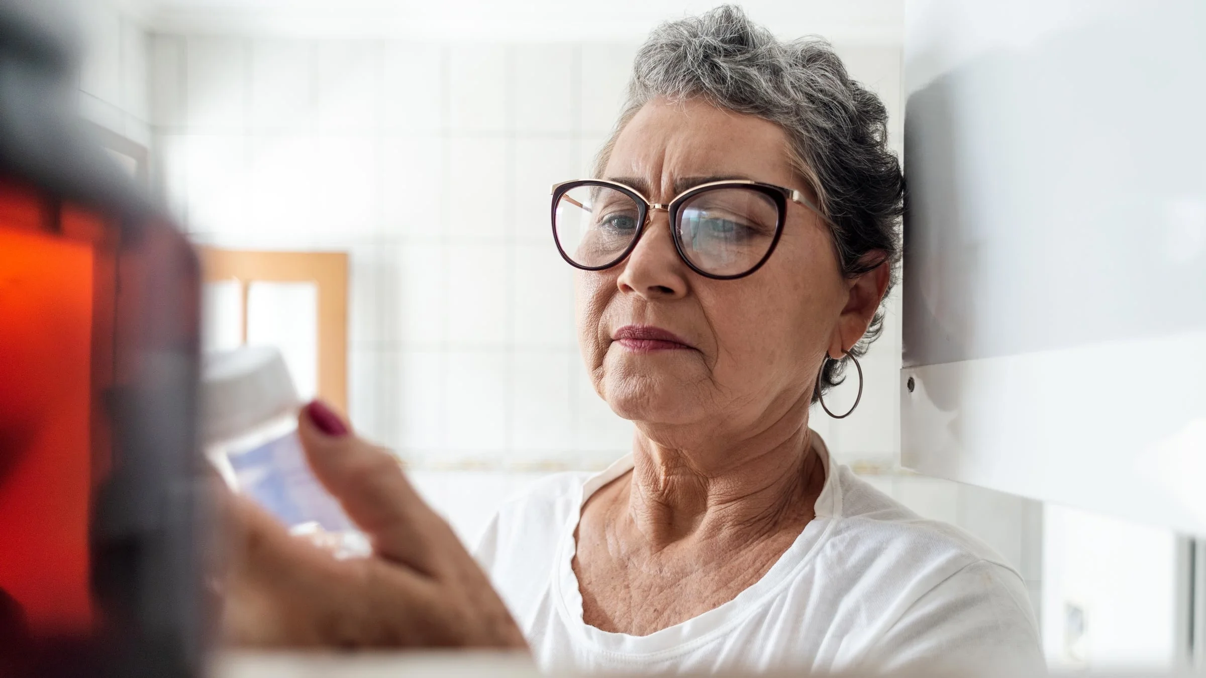 A woman reads a prescription medication bottle.
