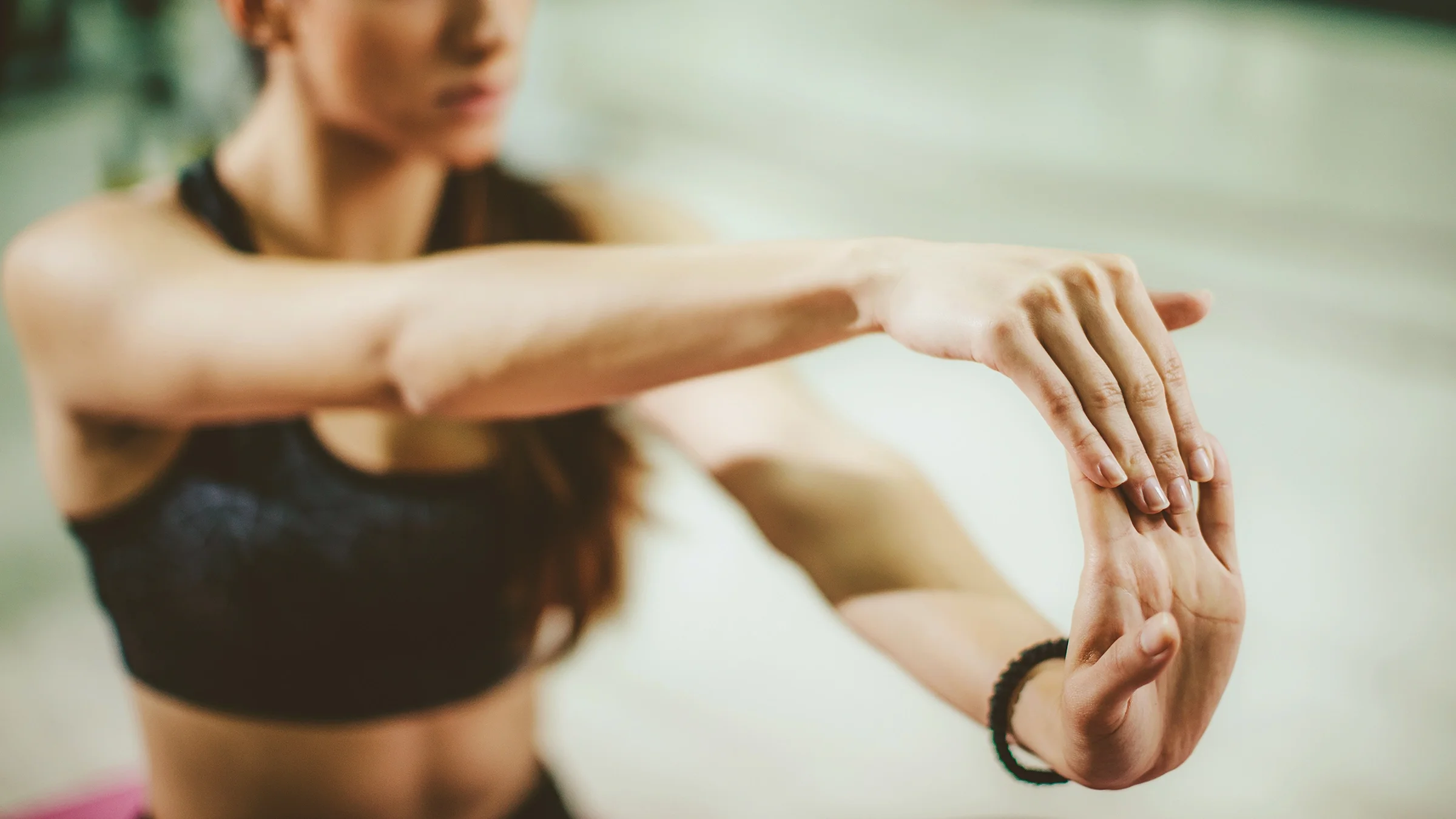 Cropped shot of a woman stretching her wrists. She is wearing workout clothes.